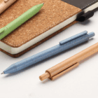Three Event Branded Eco-Friendly Wheat Pens and a cork notebook on a white surface.