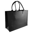 A black tote bag with sturdy, rectangular design and double handles is shown. The bag is plain, with a smooth texture and reinforced stitching at the handle attachments. It stands upright against a white background.