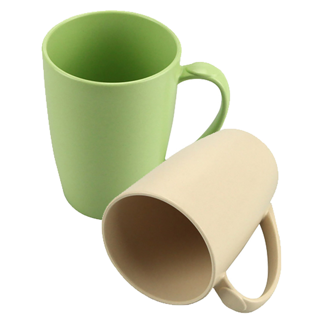 A green mug and a beige Eco Bamboo Mugs Bulk Printed, one upright, one lying on its side.