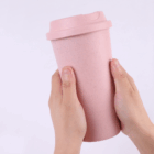 Two hands hold a pink Phoenix Reusable Eco Coffee Cup with lid against a light background.