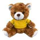 A brown teddy bear wearing a yellow shirt sits facing forward.