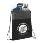 Black drawstring bag with Sage Philosophy text, filled with travel magazines and brochures.