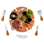 Cheese board with grapes, meat, olives, wine, and knives arranged in a circular pattern.