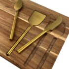 Gold cheese knives on a wooden board with slots for storage.
