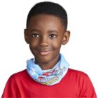 Smiling child in a red shirt and blue scarf against a white background.