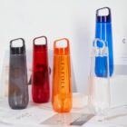 Five colorful plastic water bottles on a marble surface.