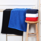 Large promotional cotton gym towels stacked on a stool, more draped nearby.