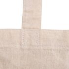 Close-up of a linen or cotton fabric, showing the woven texture and stitching details. A strap is attached at the top with a visible sewn X for reinforcement. The fabric is beige, suggesting a natural, unbleached material.
