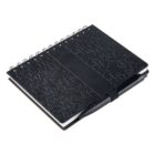 A black spiral-bound notebook with a textured, geometric cover lies closed. A matching black pen is tucked into a holder on the right side of the notebook.