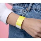 Person wearing a yellow wristband on their left wrist, wearing jeans and a white shirt.