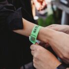 Close-up of hands securing a green wristband with a QR code on someone’s wrist.