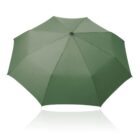 A large, open, green umbrella viewed from above, showing its radial panels and central hub against a white background. The umbrellas reflection is slightly visible below it.