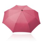 A red umbrella with a black handle is fully opened, displaying its symmetrical octagonal shape. The surface appears smooth and slightly reflective, and the image is set against a plain white background.