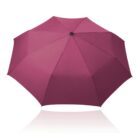A fully open magenta umbrella with a black center tip, viewed from above against a white background.