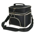 A black rectangular cooler bag with beige trim, featuring a top handle, a curved front pocket, and a detachable shoulder strap. The bag has dual zippers on both the main compartment and the front pocket.