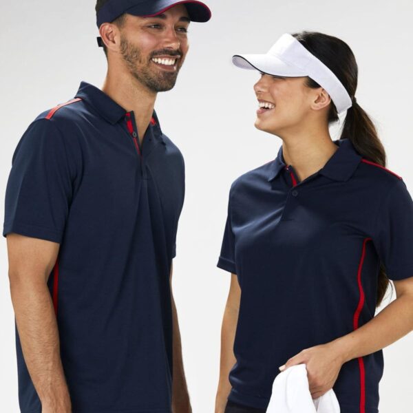 A smiling man and woman wearing navy sports polo shirts with red stripes stand side by side. The man has a black visor, and the woman has a white visor, holding a white towel against a plain background.