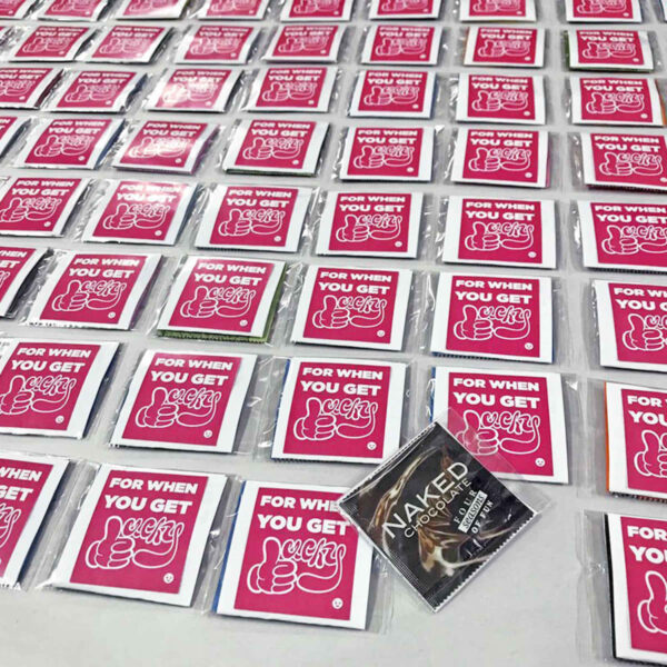 Rows of red and white packets are displayed, each labeled with For when you get lucky and a thumbs-up illustration. One packet in the foreground is different, labeled Naked Chocolates.