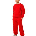 A young boy stands smiling, wearing a red tracksuit and white sneakers with gray accents. He has his hands in the pockets of his pants and is standing against a plain white background.