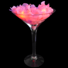 Flashing Flower Leis in a martini glass on a black background.