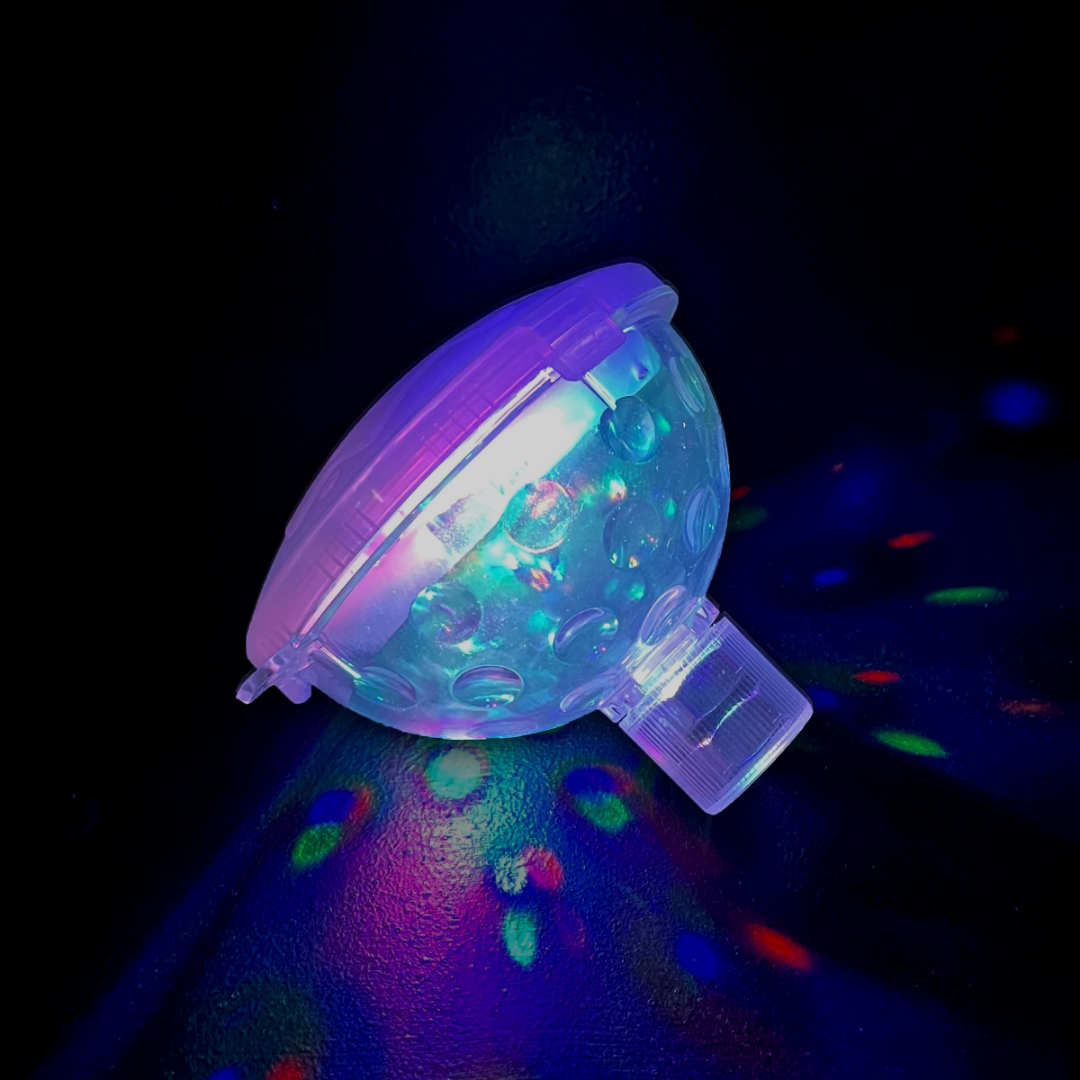 Floating Pool LED Light illuminates with colorful patterns on a dark, textured surface.