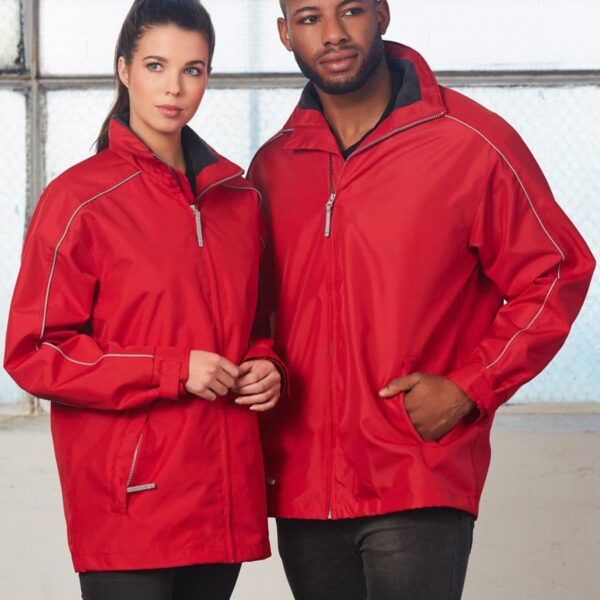 Two people wearing matching red jackets stand indoors. The jackets have silver zippers and piping. The person on the left has long dark hair tied up, while the person on the right has short hair. A large window is in the background.