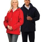 A woman in a red jacket and jeans stands next to a man in a black jacket and black pants. Both are smiling and posing against a plain white background.