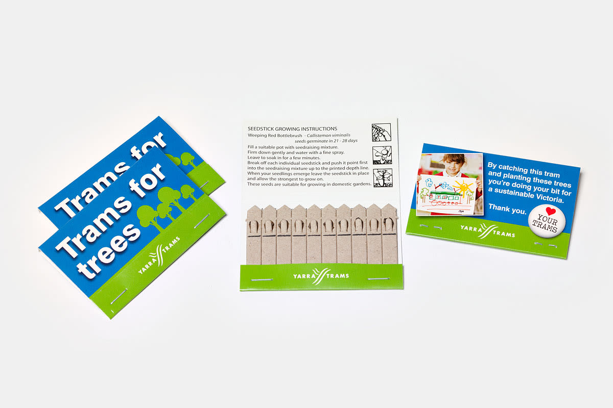 Three cards are shown: the first says Trams for trees with a tram and tree icons, the second has seedstick growing instructions, and the third features a child drawing with the words Yarra Trams. A picket fence-shaped seed packet is included.