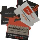 Two business card designs in the shape of a house, one mostly black with orange accents, and another orange with black accents. Both feature contact information and branding for McGrath Ralstrick, emphasizing personal service as a guarantee.