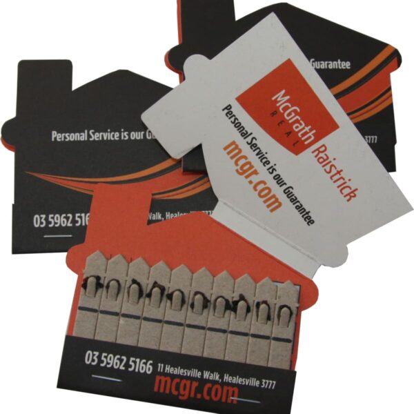 A set of house-shaped matchbooks with McGrath Raistrick branding. The matchbooks have black and orange colors, displaying contact information, a slogan Personal Service is our Guarantee, and a website URL mcgr.com.