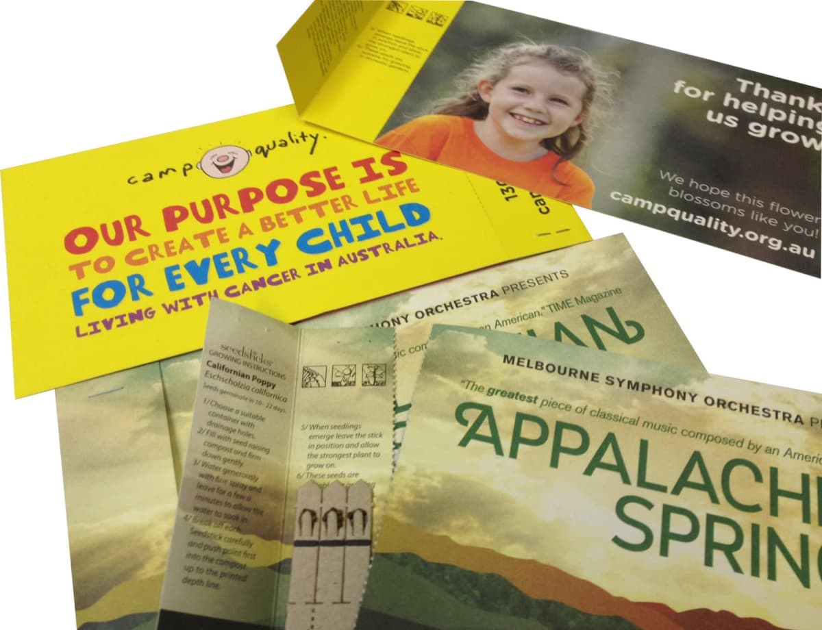 A set of brochures and envelopes displayed. One reads, Our purpose is to create a better life for every child living with cancer in Australia from Camp Quality. Another promotes the Melbourne Symphony Orchestras performance of Appalachian Spring.