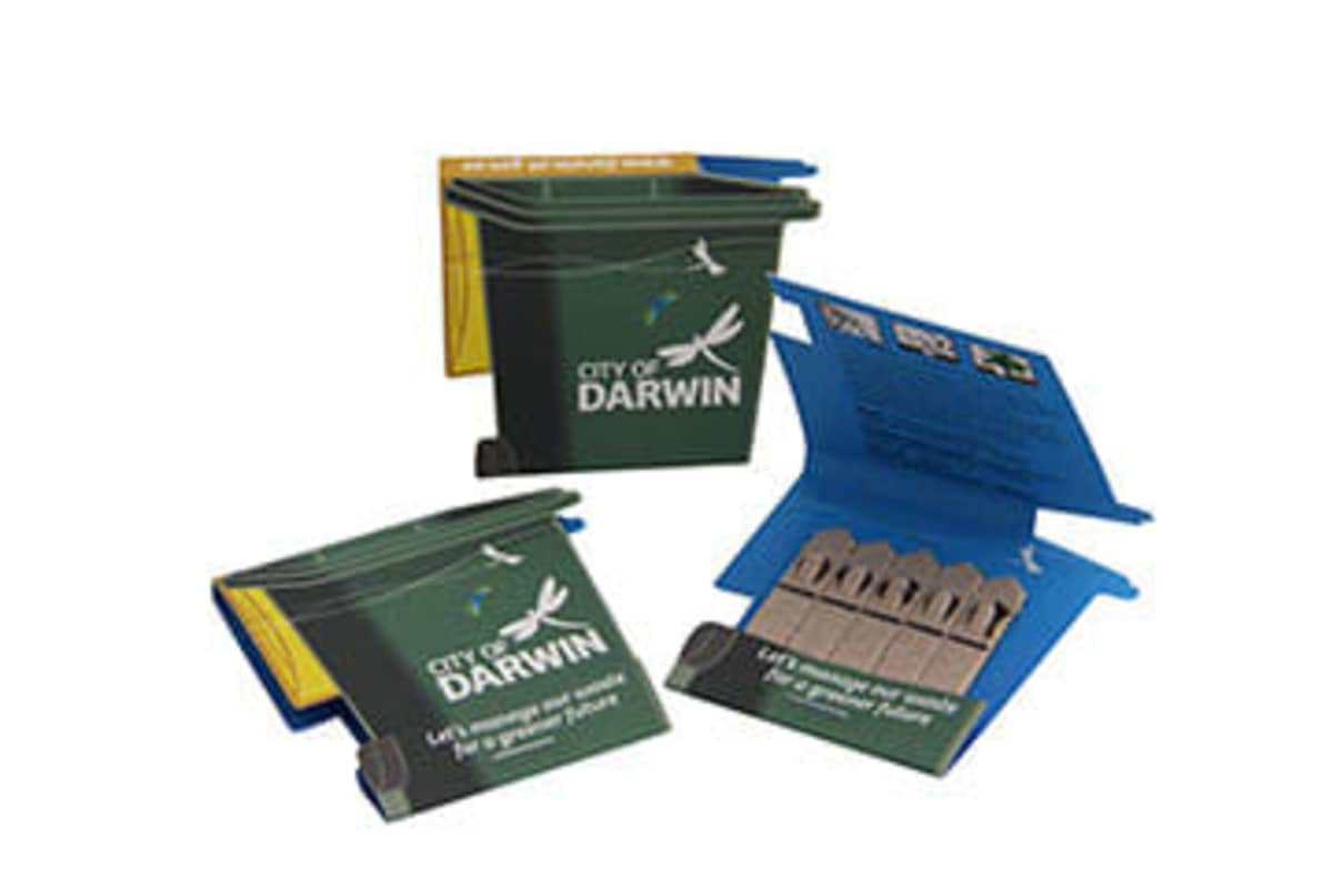 Three packets resembling miniature green recycling bins with the text City of Darwin on the side. Each packet contains small plantable seed sticks. The lids of the packets are open, revealing the sticks inside.