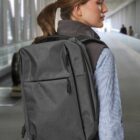 Person with a gray backpack walks through a modern airport terminal.