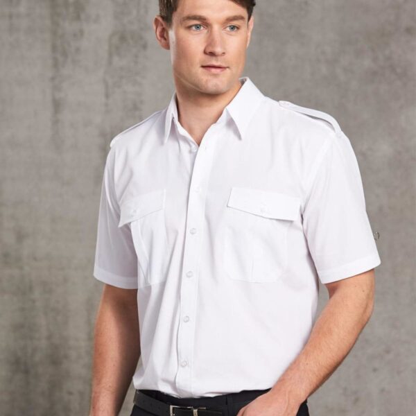Man in a white short-sleeve button-up shirt standing against a gray background.