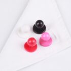 Four button pins in white, black, red, and pink on a folded white shirt.