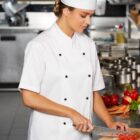Chef in a white uniform chops vegetables in a professional kitchen.