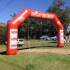 Bamburgh Angled Corner Inflatables red arch reads Bright Brewery among tents and trees.
