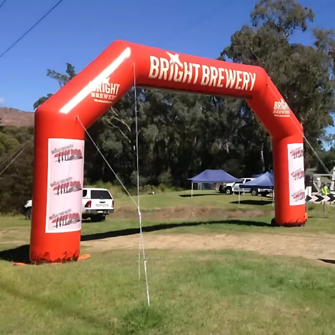 Bamburgh Angled Corner Inflatables red arch reads Bright Brewery among tents and trees.