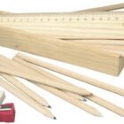 Wooden box with colored pencils, a ruler, eraser, and red sharpener spread around.