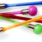 A collection of colorful ballpoint pens with rubber bulb tops in various colors, including blue, purple, green, orange, and red, scattered on a white surface.