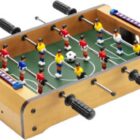 Tabletop foosball game with red and yellow teams and a small soccer ball in play.