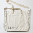 White tote bag with bizcare logo and doodle accents on the sides.
