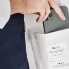 Hand placing a smartphone into a coat pocket labeled bizcare.
