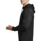 Man wearing a black hoodie with a Nike logo, standing sideways with hands together.