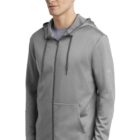 Man wearing a light gray zip-up hoodie with pockets, standing against a white background.