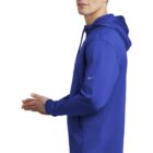Man in a blue hooded sweatshirt standing sideways with hands together, looking forward.