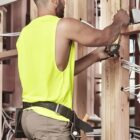 A construction worker measures wood beams at a building site.