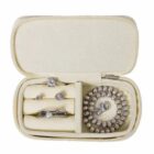 Small cream jewelry case holding rings, earrings, and a beaded bracelet with clasp.