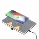 A smartphone wirelessly charging on top of a gray fabric-covered notebook.
