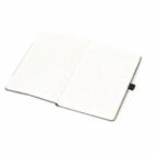 Open lined notebook with a black cover, lying on a white surface.