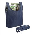 Reusable blue tote bag holding magazines and bottles, with a rolled-up bag beside it.
